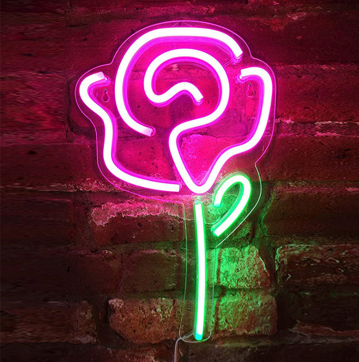 Neon sign shaped like a heart with a green stem against a brick wall.