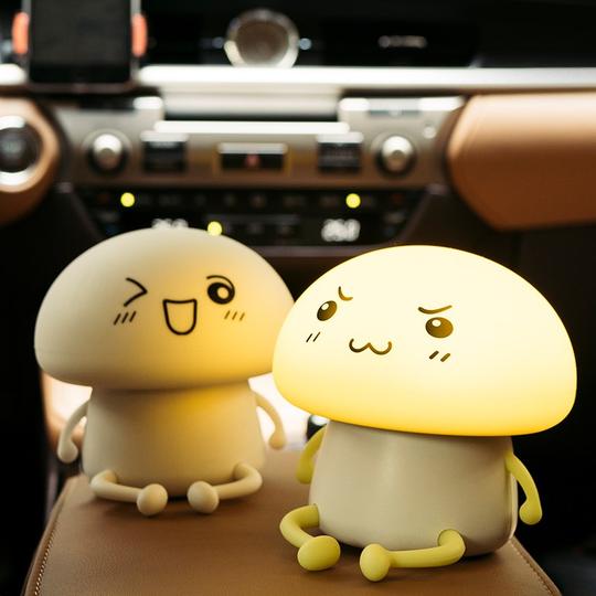 Two mushroom-shaped night lights with cartoon faces on a car dashboard.
