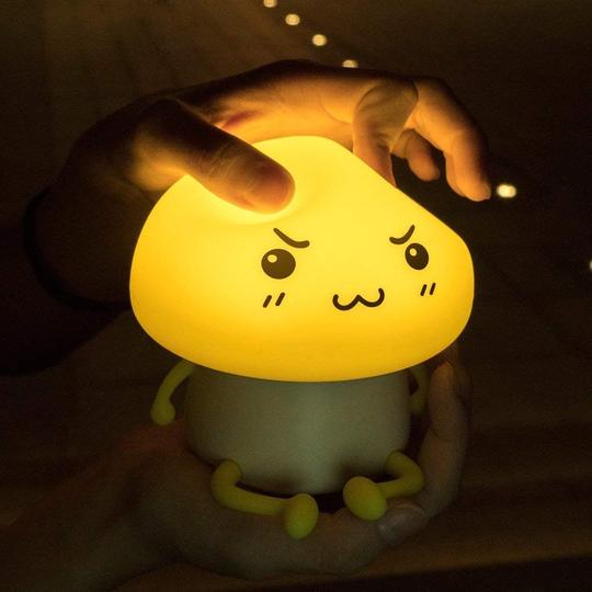 Cute lamp shaped like a cartoon character being held in a hand with a dark background